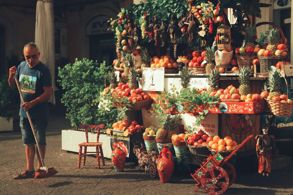 Fruit stall vendor sweeping at Italian market