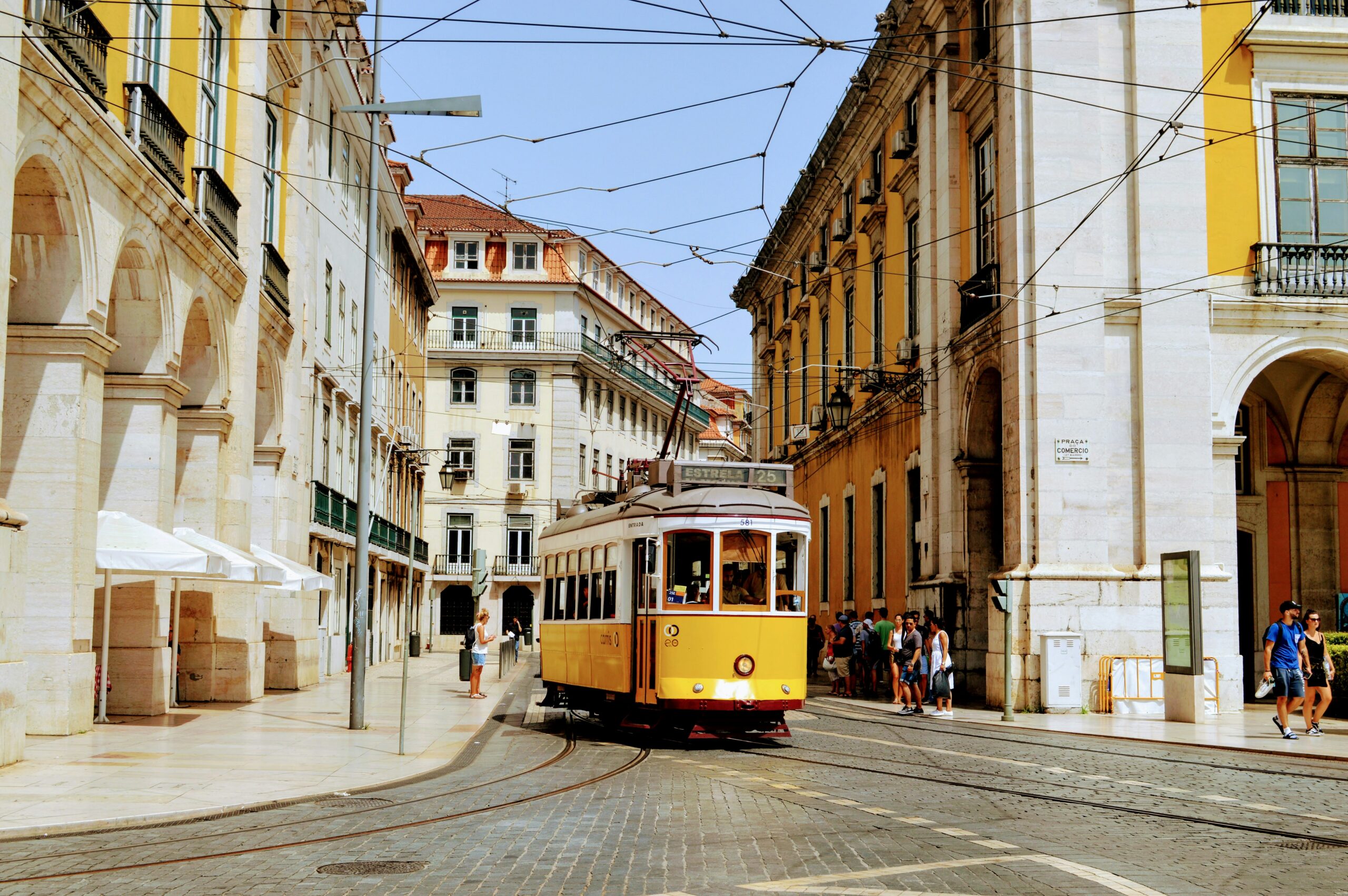 Yellow tram moving through the sunny streets of Portugal
