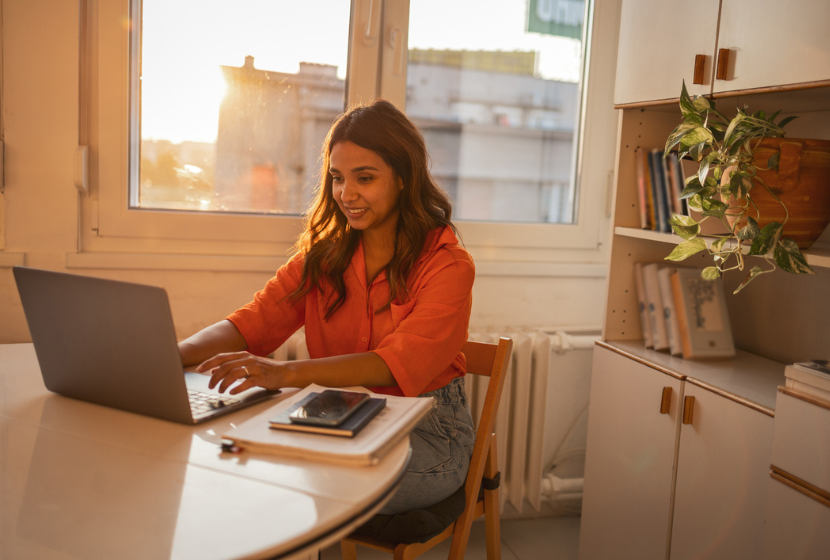 Smiling young woman looking at her laptop in a European apartment
