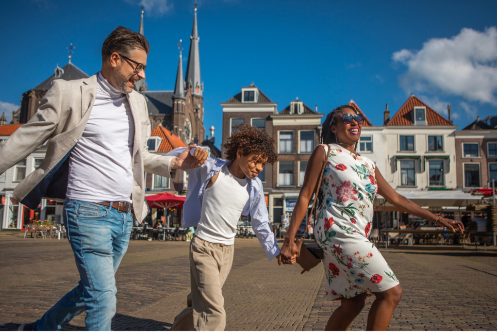 Mother, father, and child holding hands and skipping happily through a European city