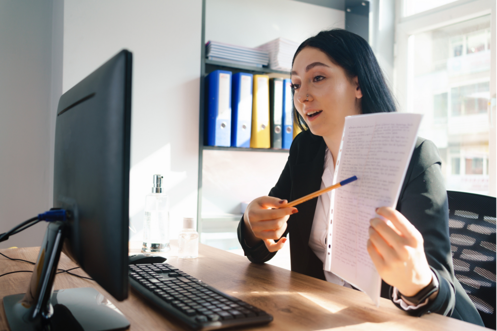 Woman working on a computer pointing at documents