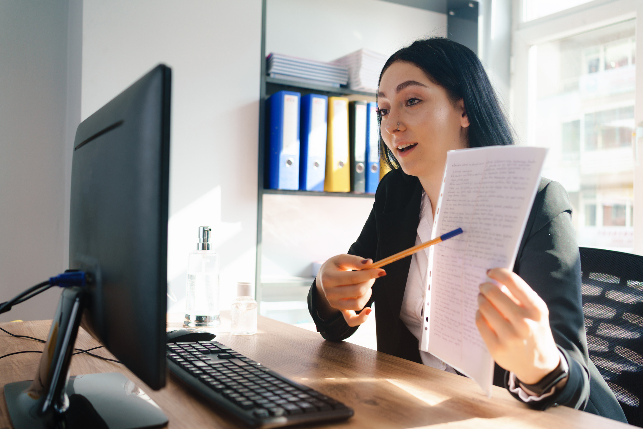 Woman working on a computer pointing at documents