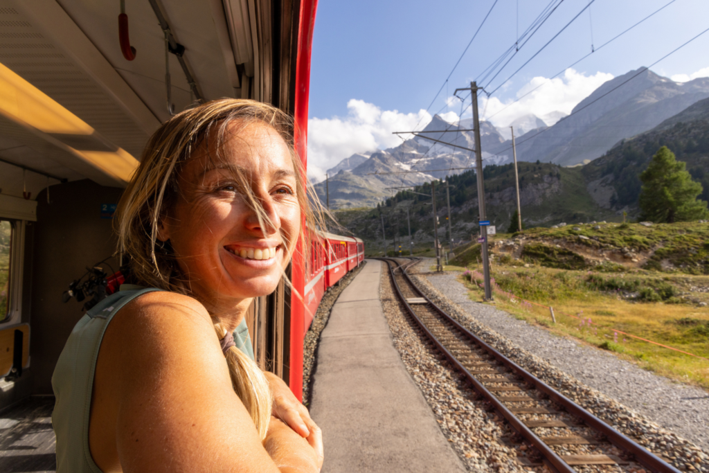 Smiling woman looks out of red train window