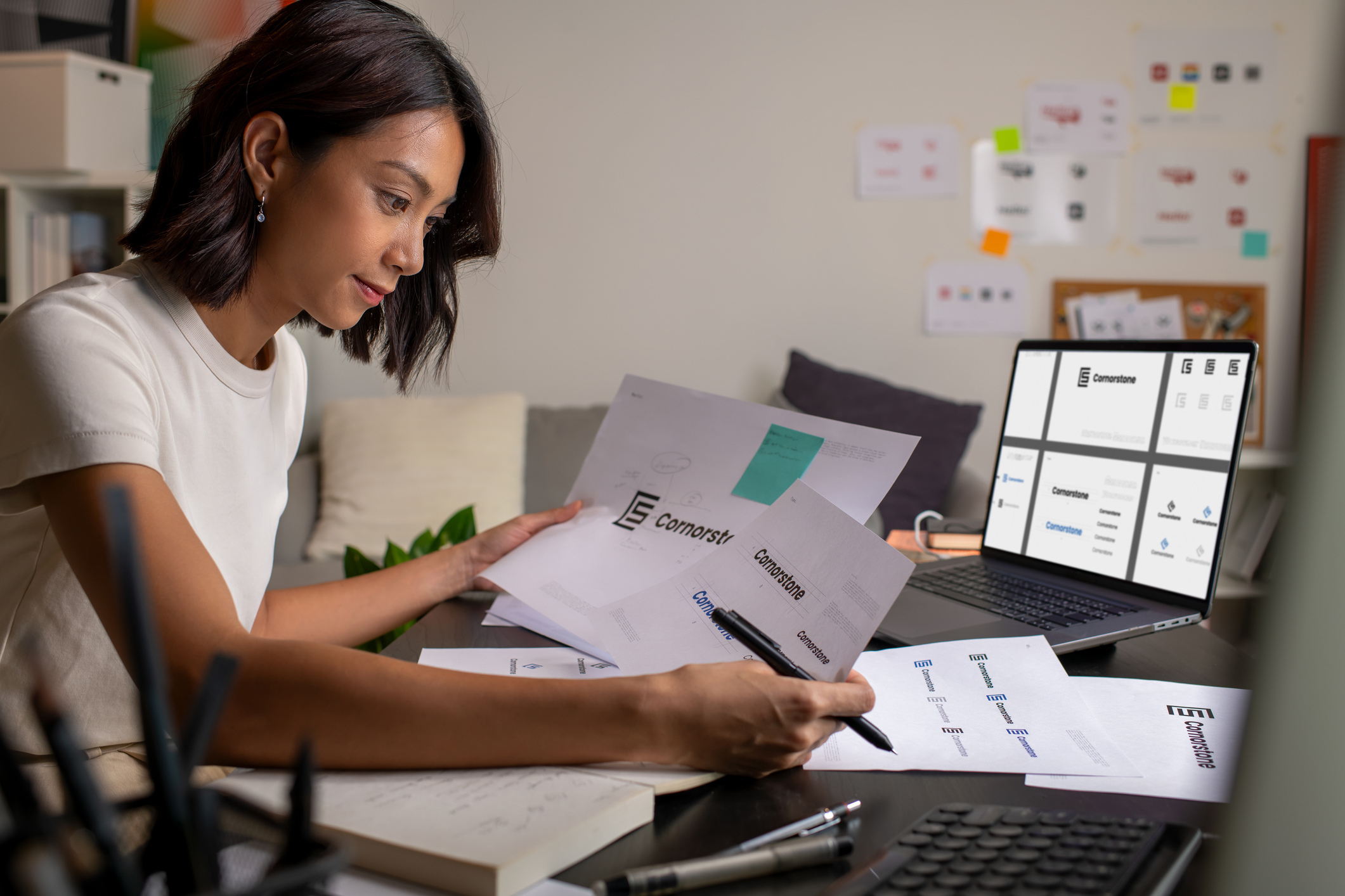 Woman performing freelance work on a laptop with documents in her hands