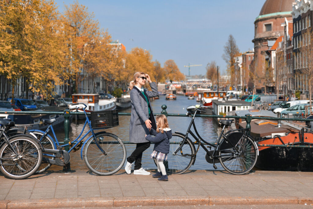 Blonde Dutchwoman mother with her daughter near the bicycle on the bridge over the water channel in Amsterdam city