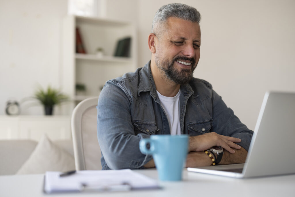 Smiling man looking at a laptop