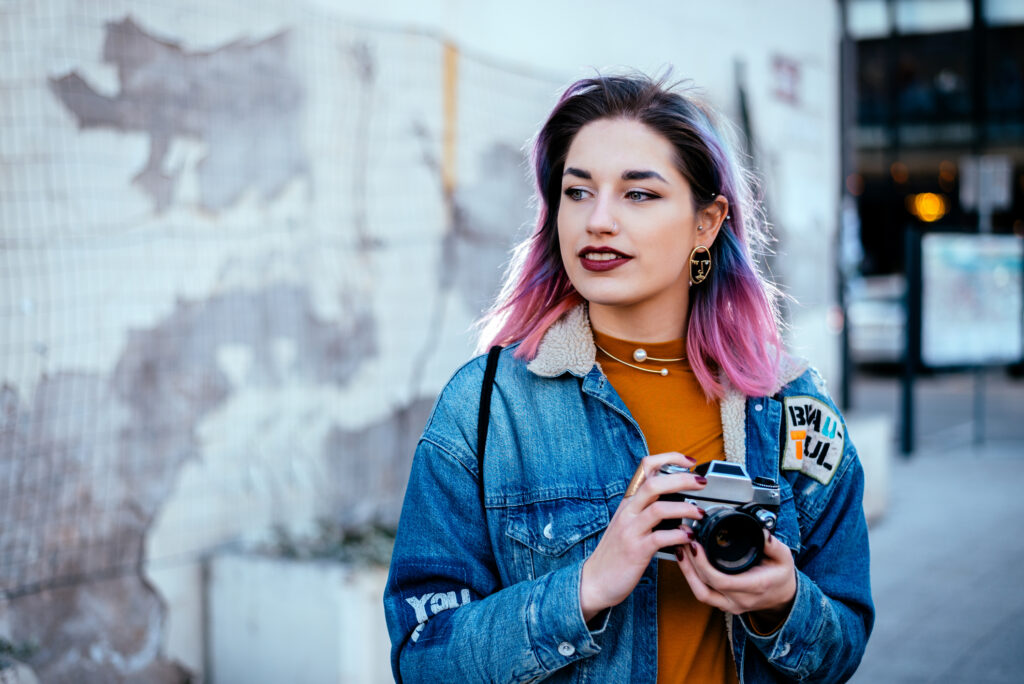 Beautiful urban girl photographer looking away, holding a camera.