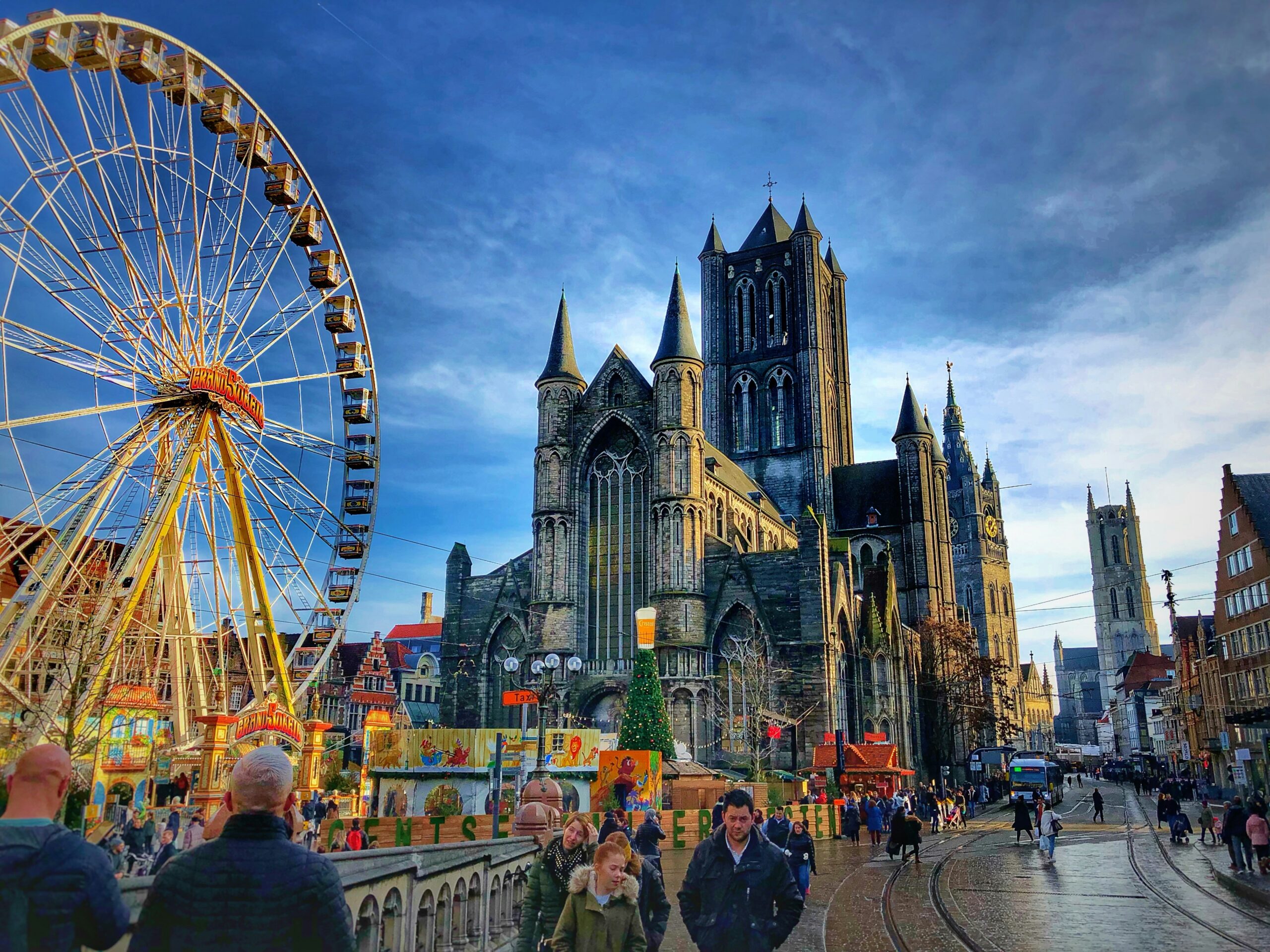 a church with a fair in front of it on a street filled with pedestrians in Belgium