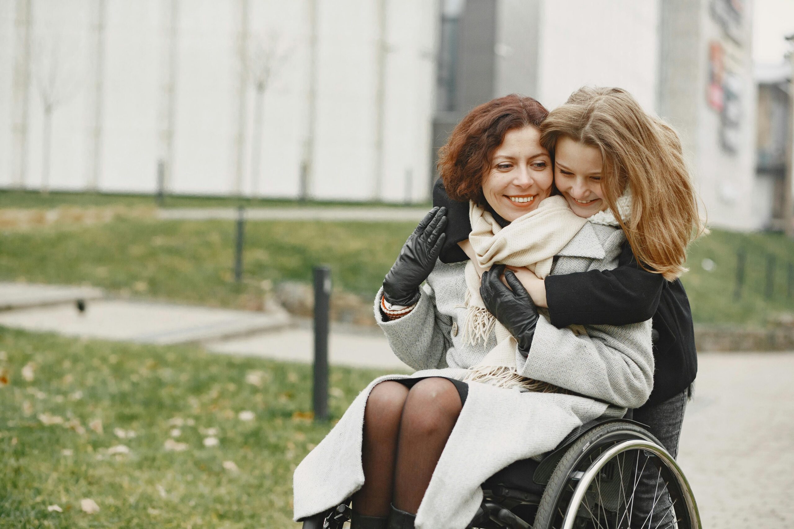 Happy woman in a wheelchair is hugged by her daughter