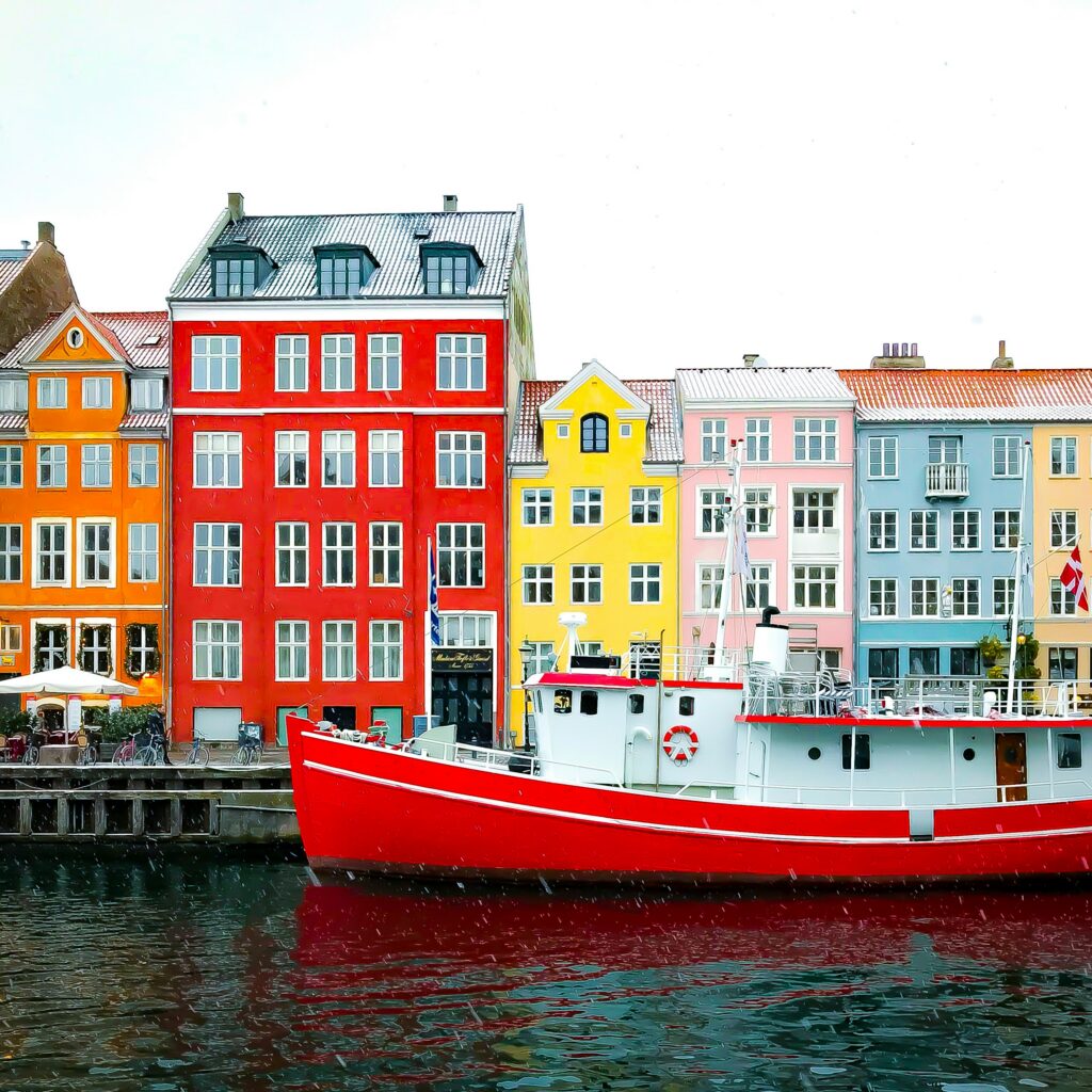 A red boat in a canal in front of colorful buildings in Denamrk