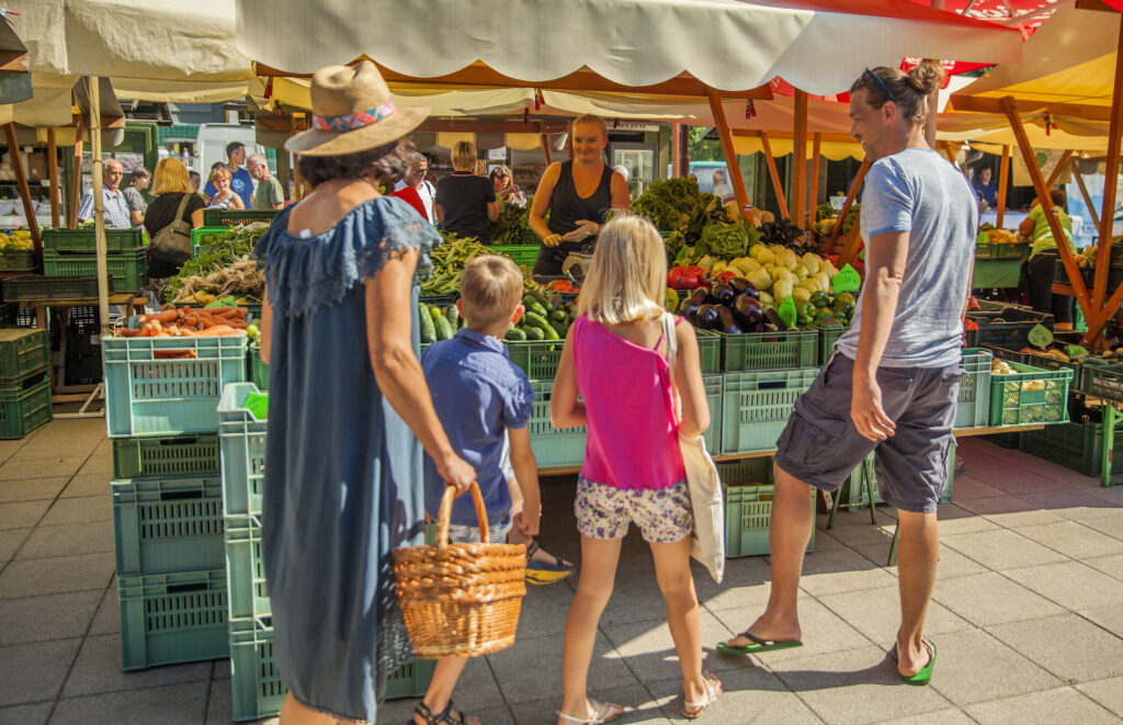 A sunny Saturday morning at farmer's market. A family is buying groceries.
