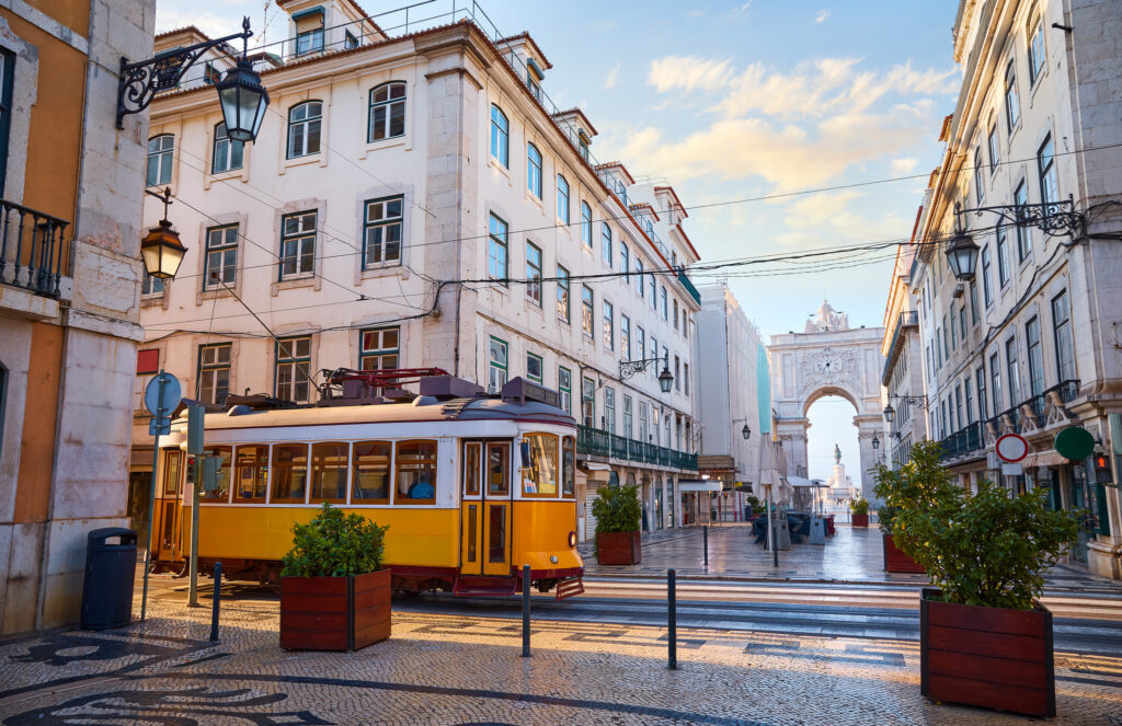 Lisbon, Portugal. Yellow touristic retro tram. Triumphal Arch of Rua Augusta near Praca do Comercio (Commercial Square. Sunny day in famous tourist place Lisboa.