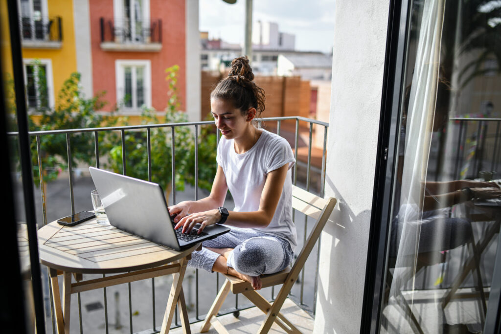 A woman working on a laptop from a balcony in Valencia, Spain