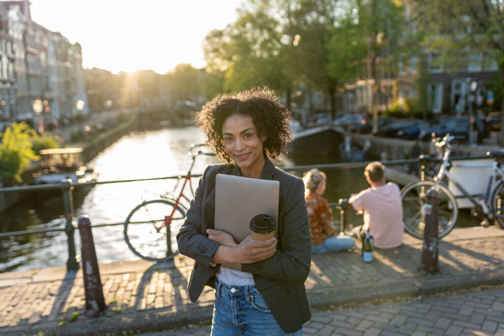 Businesswoman with laptop on bridge in Amsterdam.