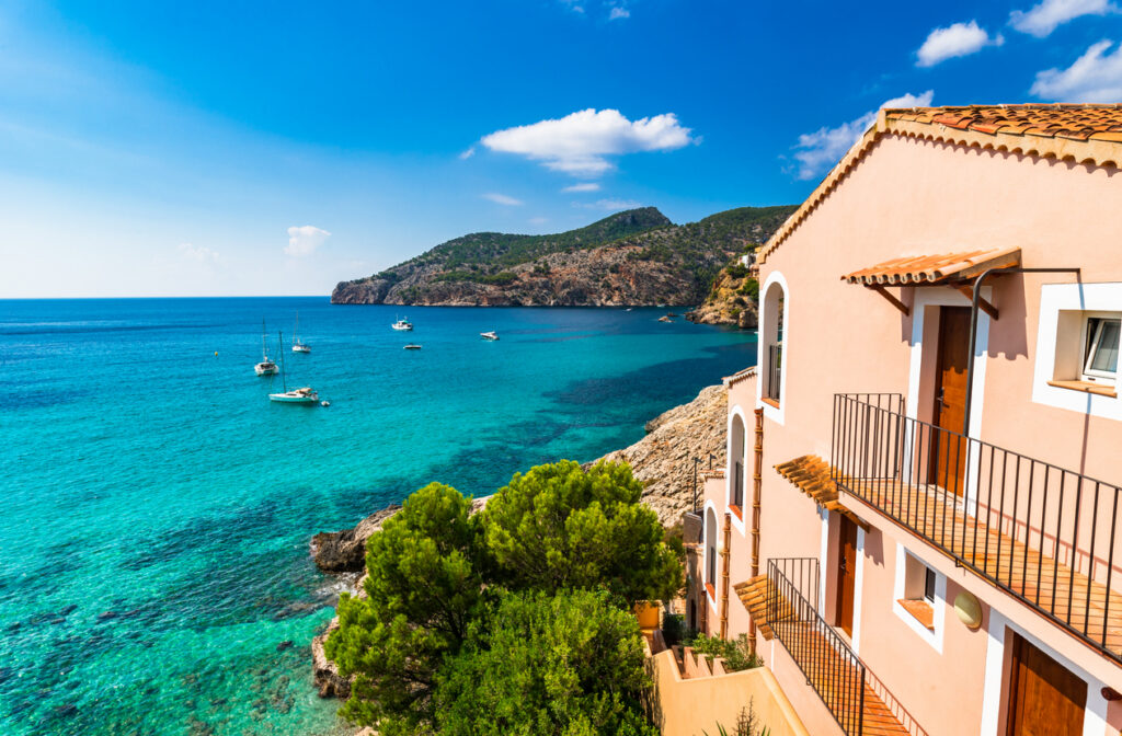 pastel colored home in Spain overlooking the clear blue sea with boats